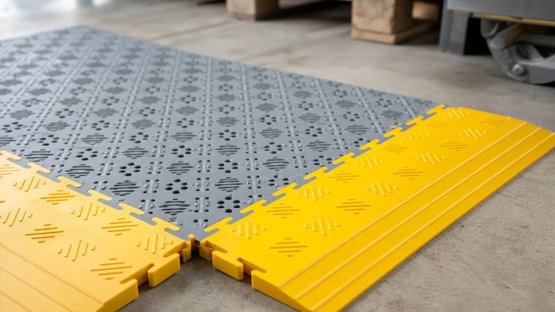 Wasserdurchlässiger Flexi-Tile Open Bodenbelag in Grau mit gelben Anlauframpen, ideal für Bereiche mit stehendem Wasser.